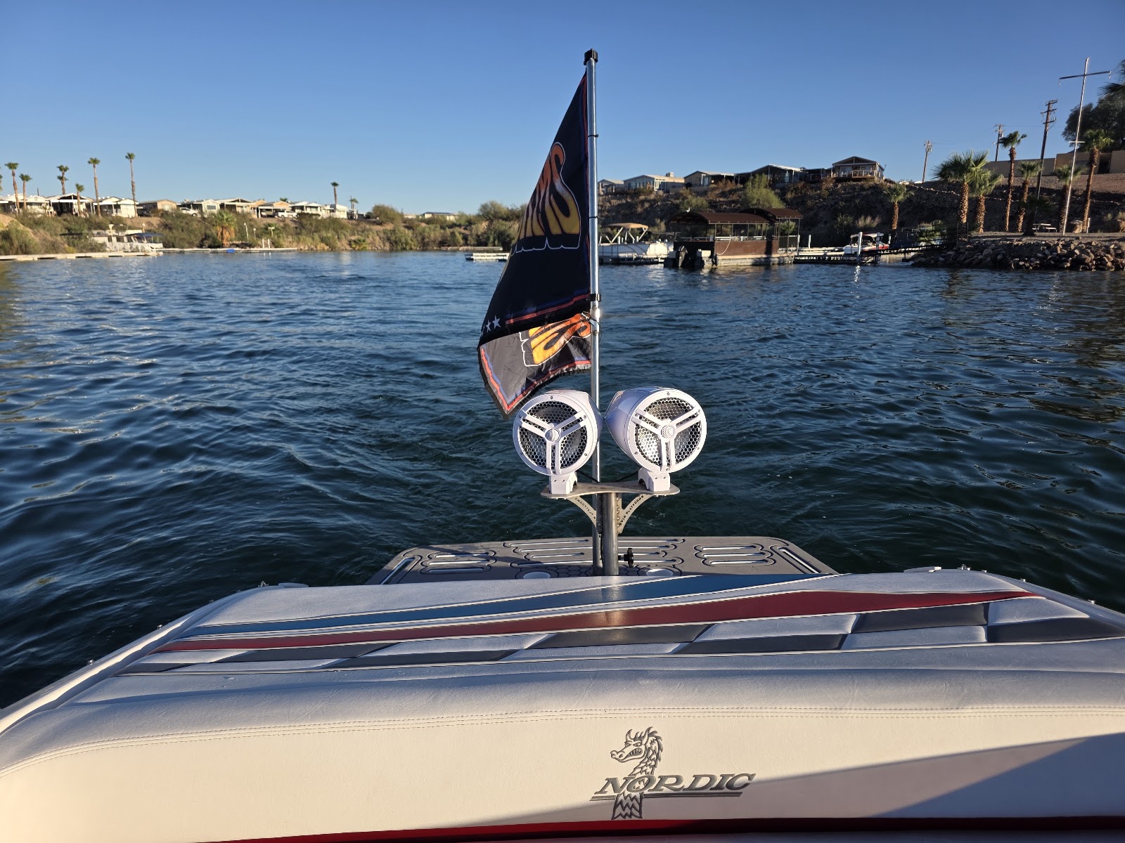 Speaker pods and a flag mounted over a boat swim platform on the lake