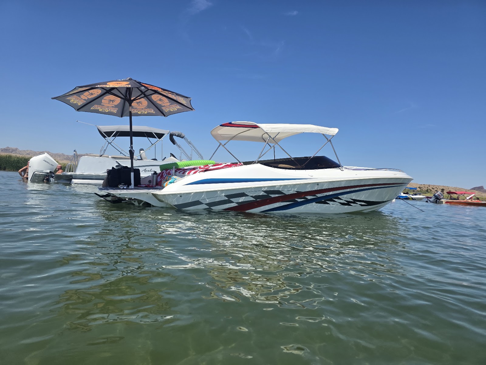 Boats anchored on the lake under Sandbar Shade umbrellas