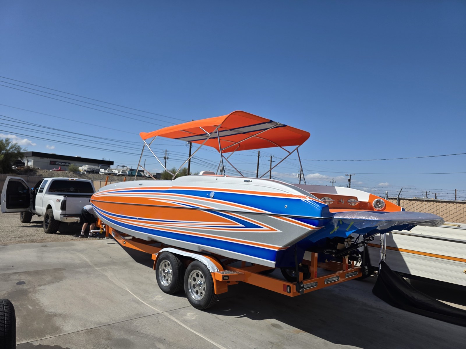 Orange and blue performance boat with a matching orange bimini under a clear blue sky