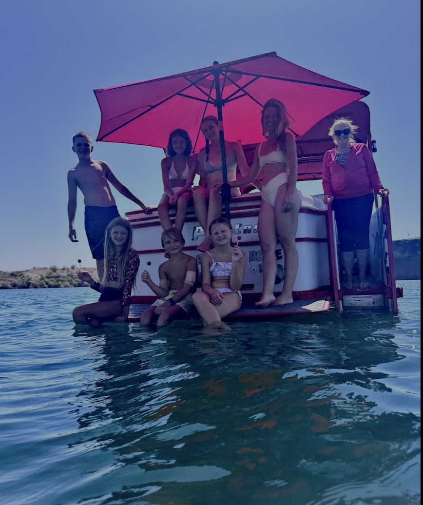 Family relaxing on a boat under a pink Sandbar Shade umbrella