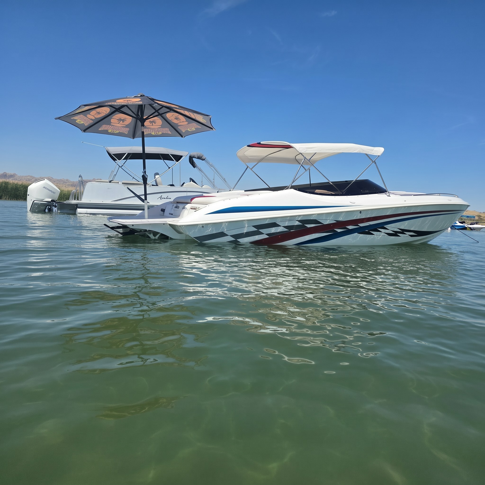 White performance boat rafted alongside a pontoon boat on a calm lake, a black and orange Sandbar Shade umbrella mounted over its swim platform