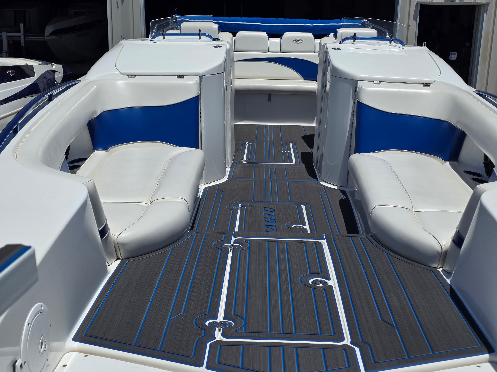 Boat cockpit floor finished in gray marine decking with blue accent lines between white and blue seats