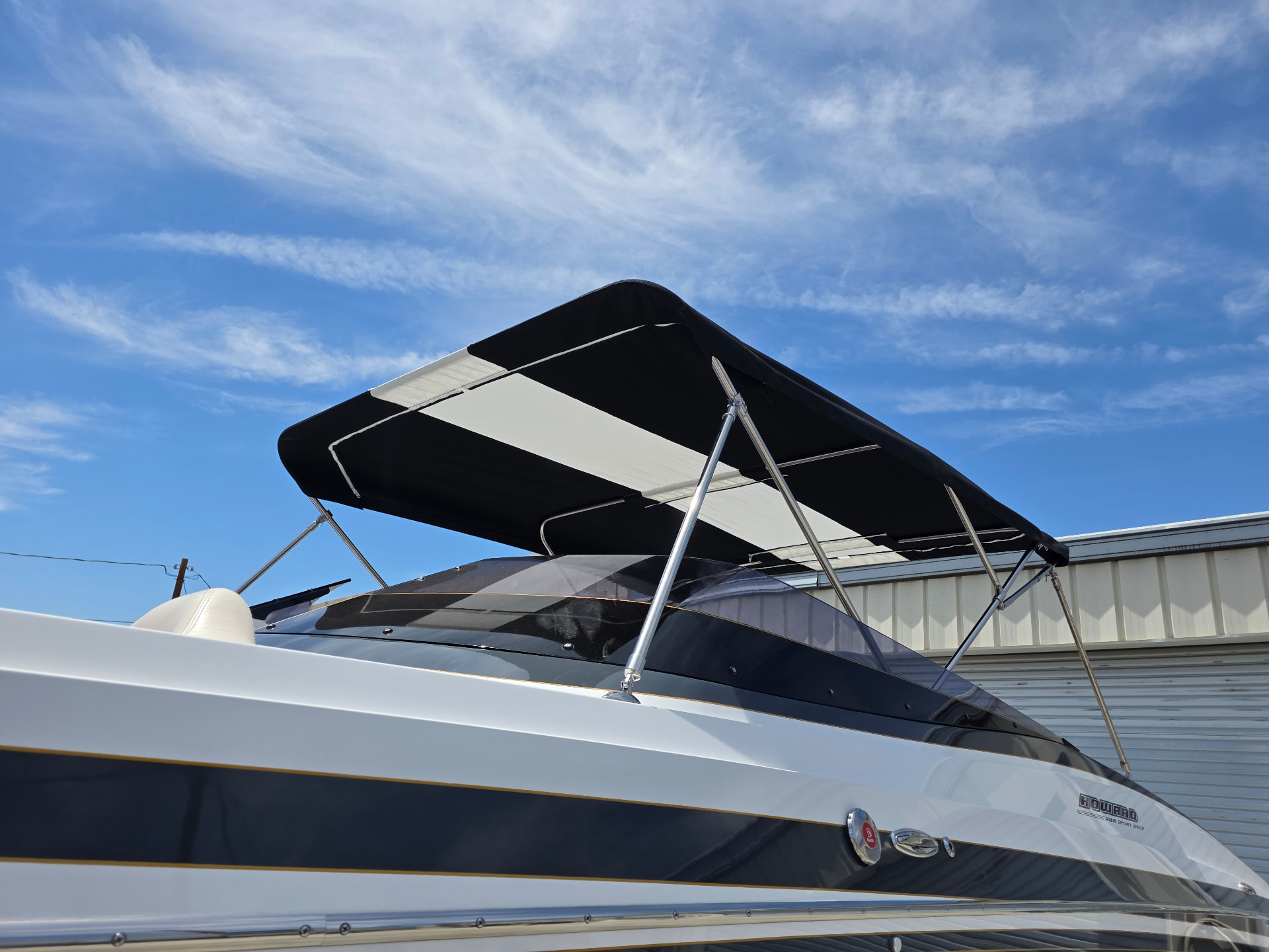 Black and white Bimini top on stainless frame over the cockpit of a black and white boat
