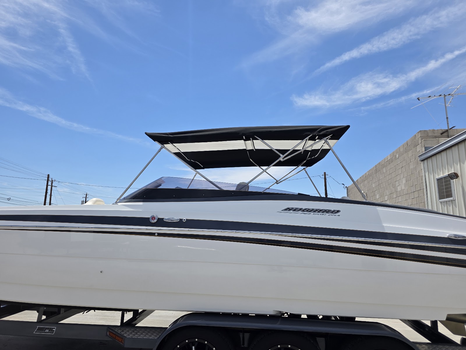 Side view of a white performance boat with a black and white bimini top