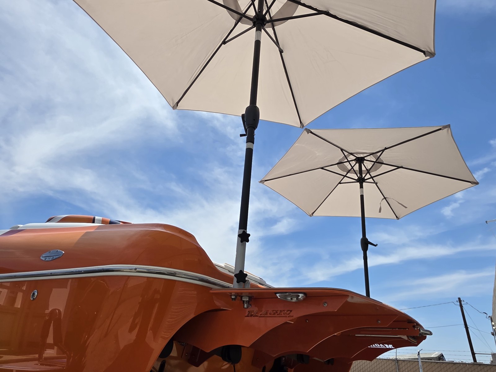 Two light colored Sandbar Shade umbrellas mounted over an orange boat
