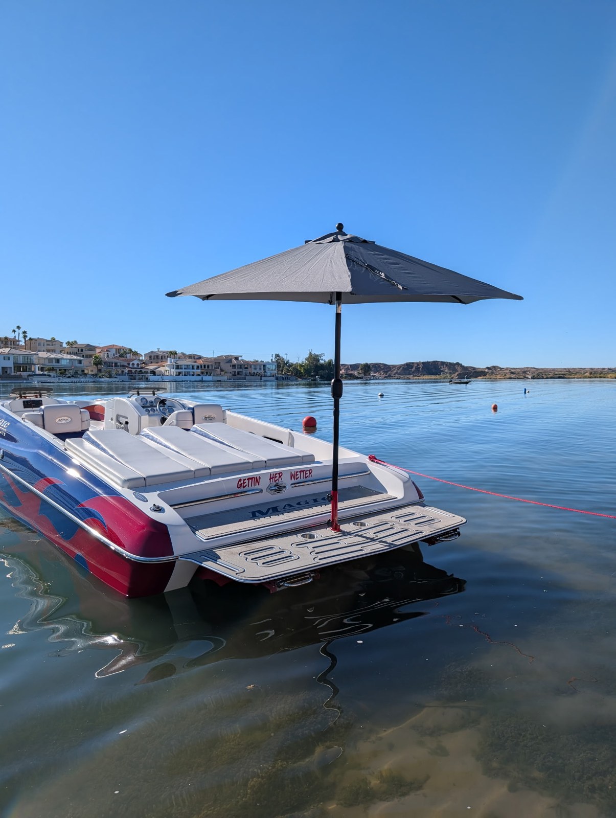 Sandbar Shade umbrella above a white boat's swim platform on a calm lake