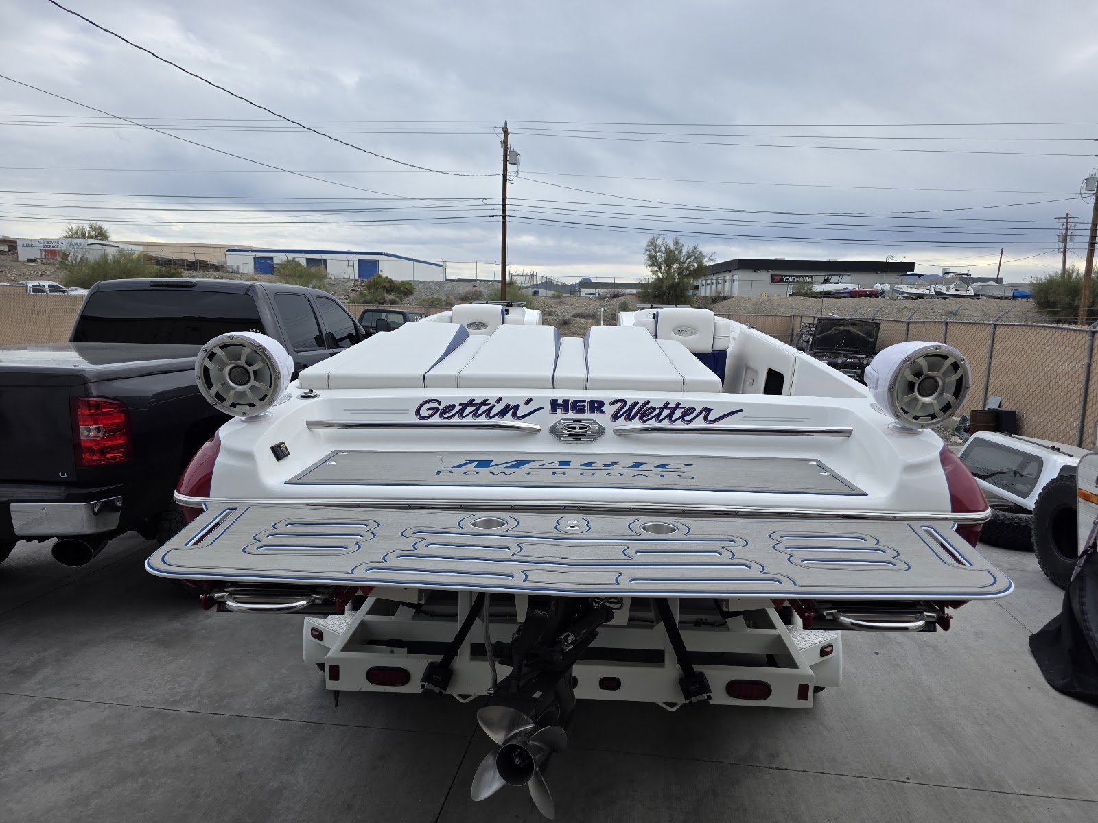 White boat on the hoist showing its custom swim platform from behind