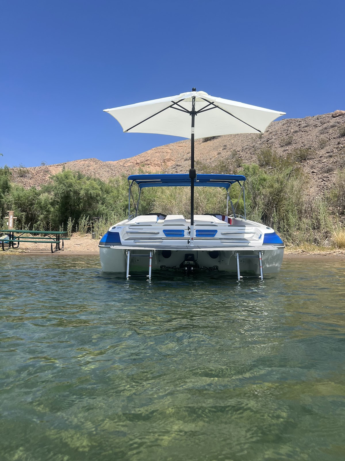 Pontoon-style boat with a white Sandbar Shade umbrella over its swim platform