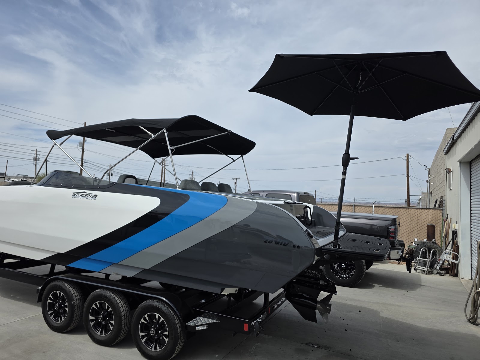 White and blue boat shaded by a black umbrella outside the shop