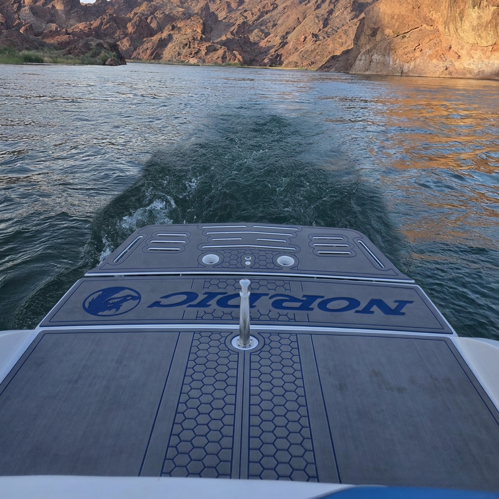 Custom gray Nordic swim platform with blue lettering extending off the stern of a boat on the Colorado River, golden desert cliffs glowing along the shoreline
